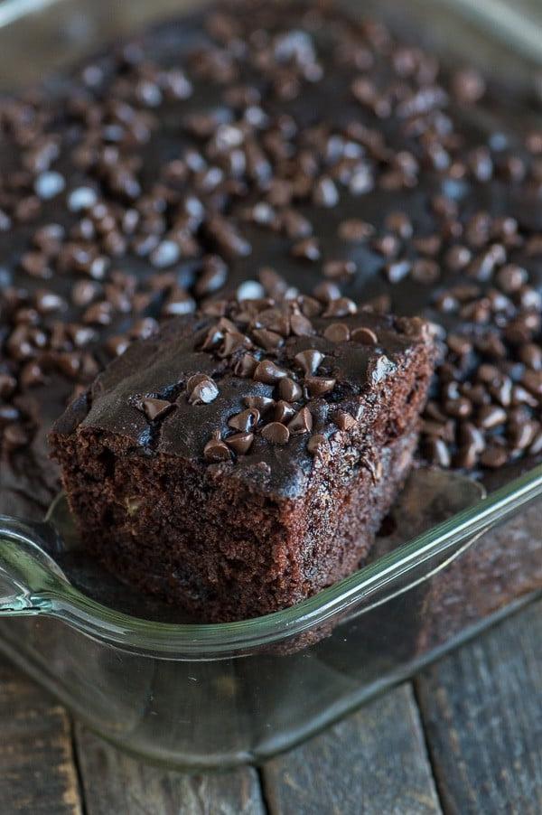 Questa torta al cioccolato più sana sa di muffin alla banana con doppie gocce di cioccolato! Niente zucchero, burro o olio, ma usa banane, yogurt greco e miele invece! Fetta di torta al cioccolato salutare in teglia di vetro