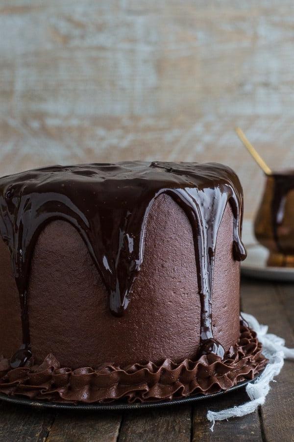 Deliziosa Torta al Cioccolato Cioccolato ricoperta di ganache al cioccolato su un tavolo di legno.