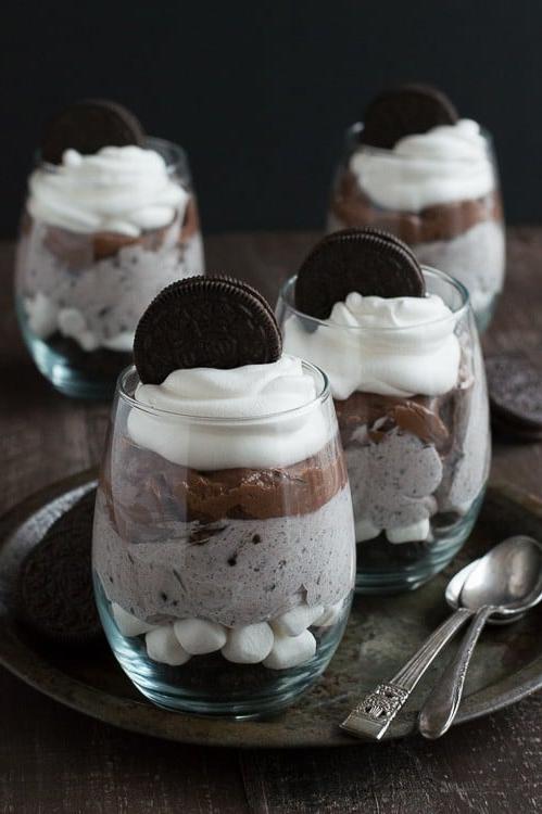 Parfait stratificato con Oreo sbriciolati, crema e cioccolato, visto dall'alto in bicchieri da dessert