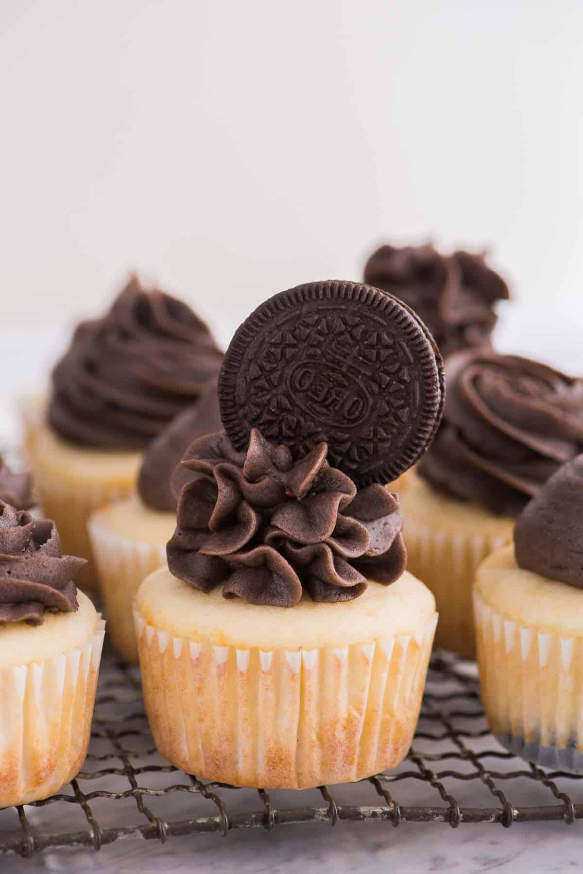 Cupcakes con base Oreo 4 Cupcakes alla vaniglia con glassa Oreo e biscotto Oreo intero in cima su una griglia di raffreddamento