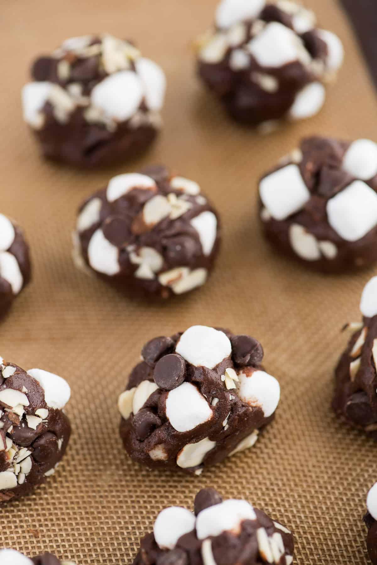 Palline di impasto per biscotti Rocky Road su un tappetino di silicone da forno, pronte per essere infornate.
