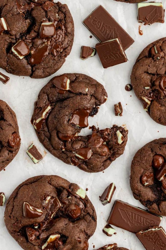 Fare Biscotti dal Mix per Torte 33 Biscotti Andes Mint su carta bianca con cioccolato fuso appiccicoso al loro interno, il biscotto centrale parzialmente aperto e pezzetti di Andes mints sparsi
