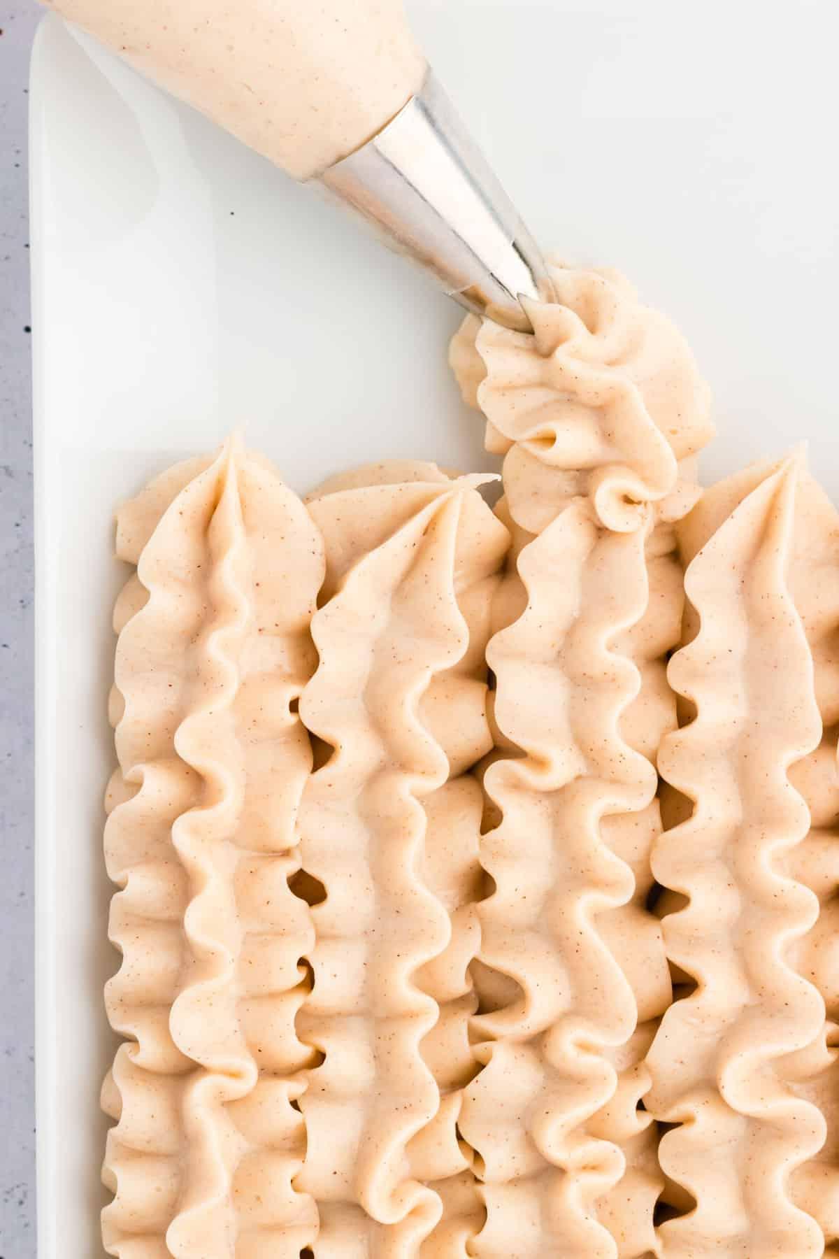 **Glassa al formaggio cremoso alla cannella** 5 Glaseado de queso crema con canela en líneas en un plato blanco