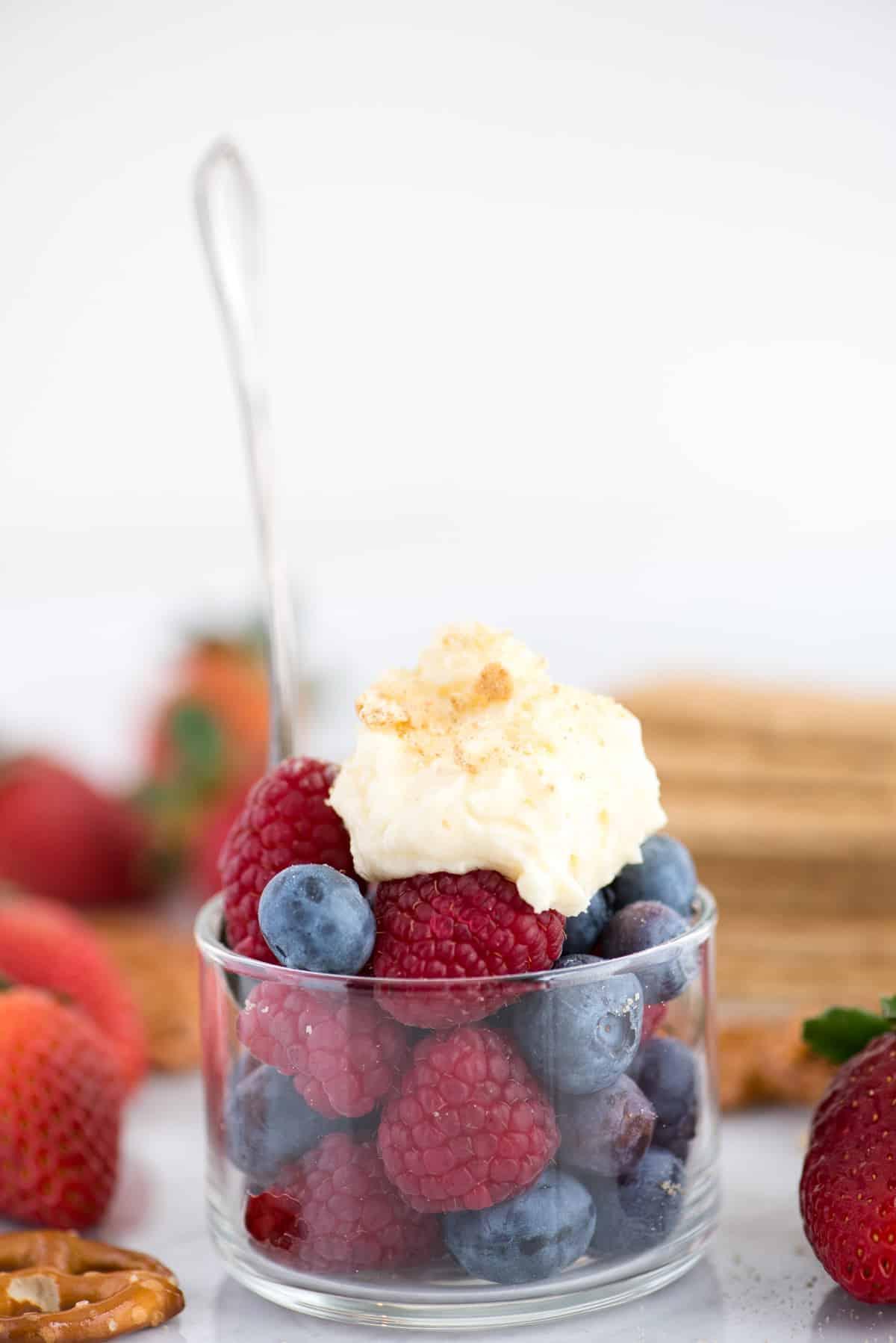 Come fare la panna montata al cheesecake stabilizzata che puoi usare su torte, cupcake, crostate e come salsa per frutta! Immagina questa panna montata al cheesecake su una crostata di fragole! #pannamonata #pannamonataaromatizzata #pannamonatacheesecake Panna montata al cheesecake su una ciotola di lamponi e mirtilli