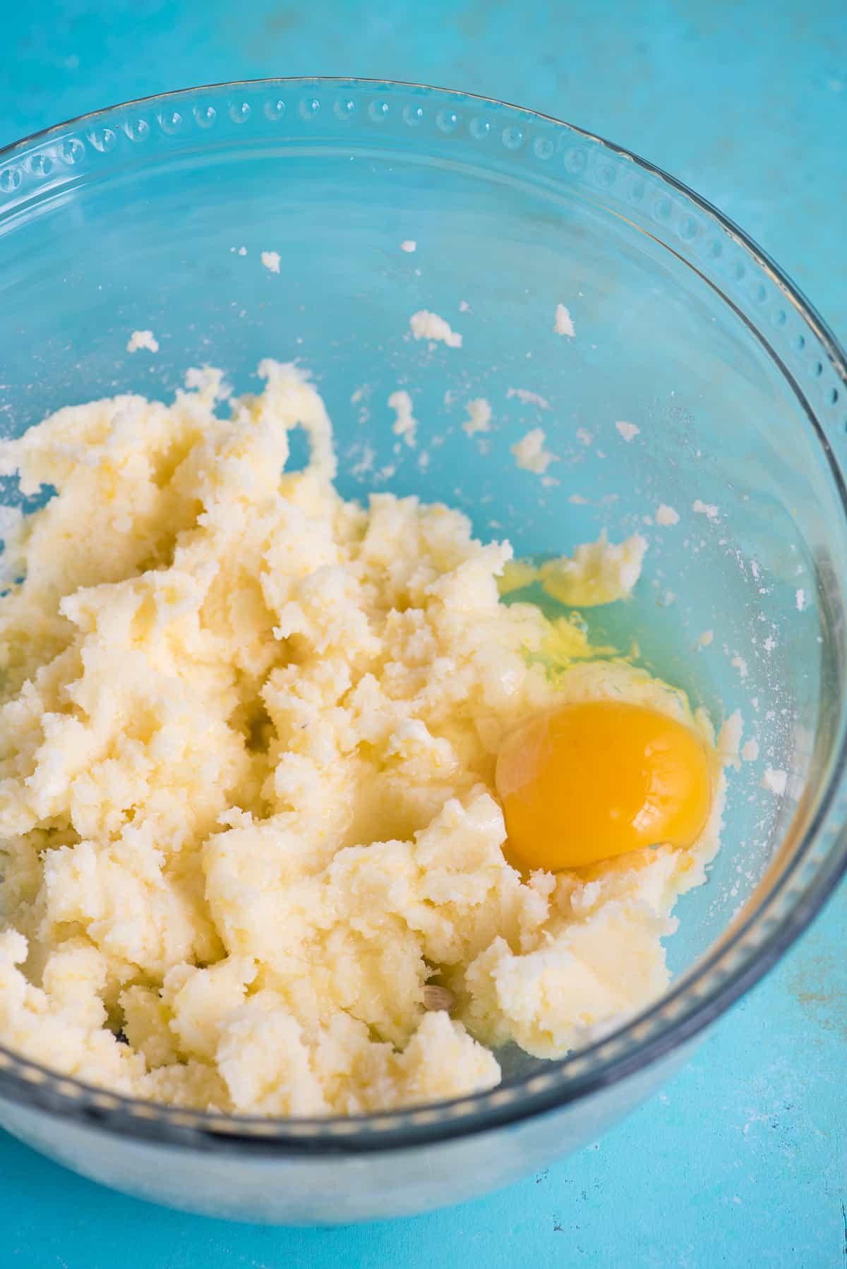 Ricetta Biscotti al Limone 5 Impasto per biscotti con uovo in una ciotola di vetro su sfondo blu