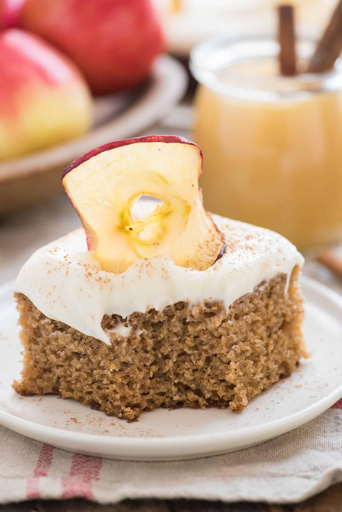 Torta Speziata alla Salsa di Mele 5 Fetta di torta di mele con glassa al formaggio cremoso e un morso rimosso su un piatto bianco