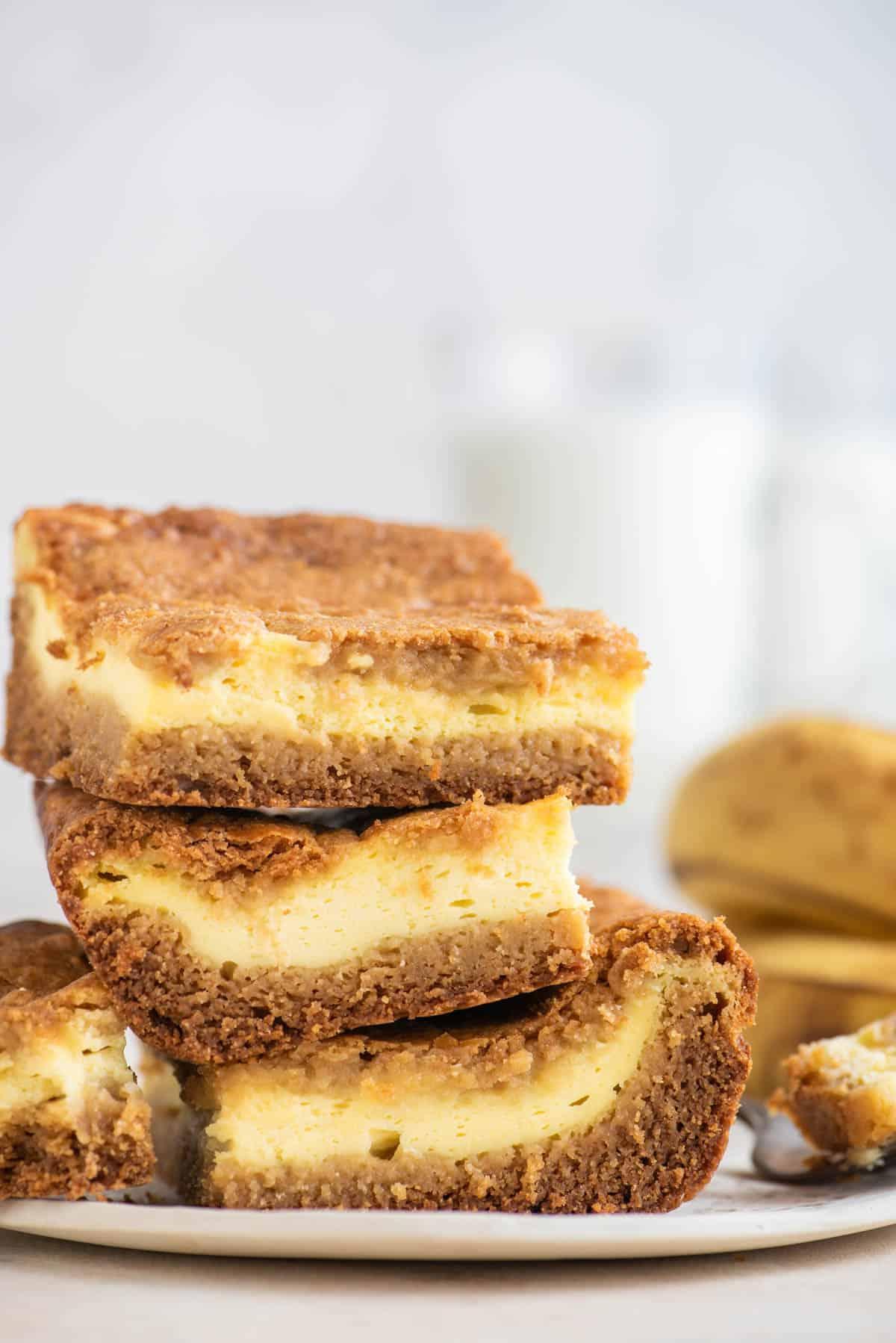Brownies al Budino di Banana 5 Tre brownies al budino di banana impilati su un piatto con banane sullo sfondo