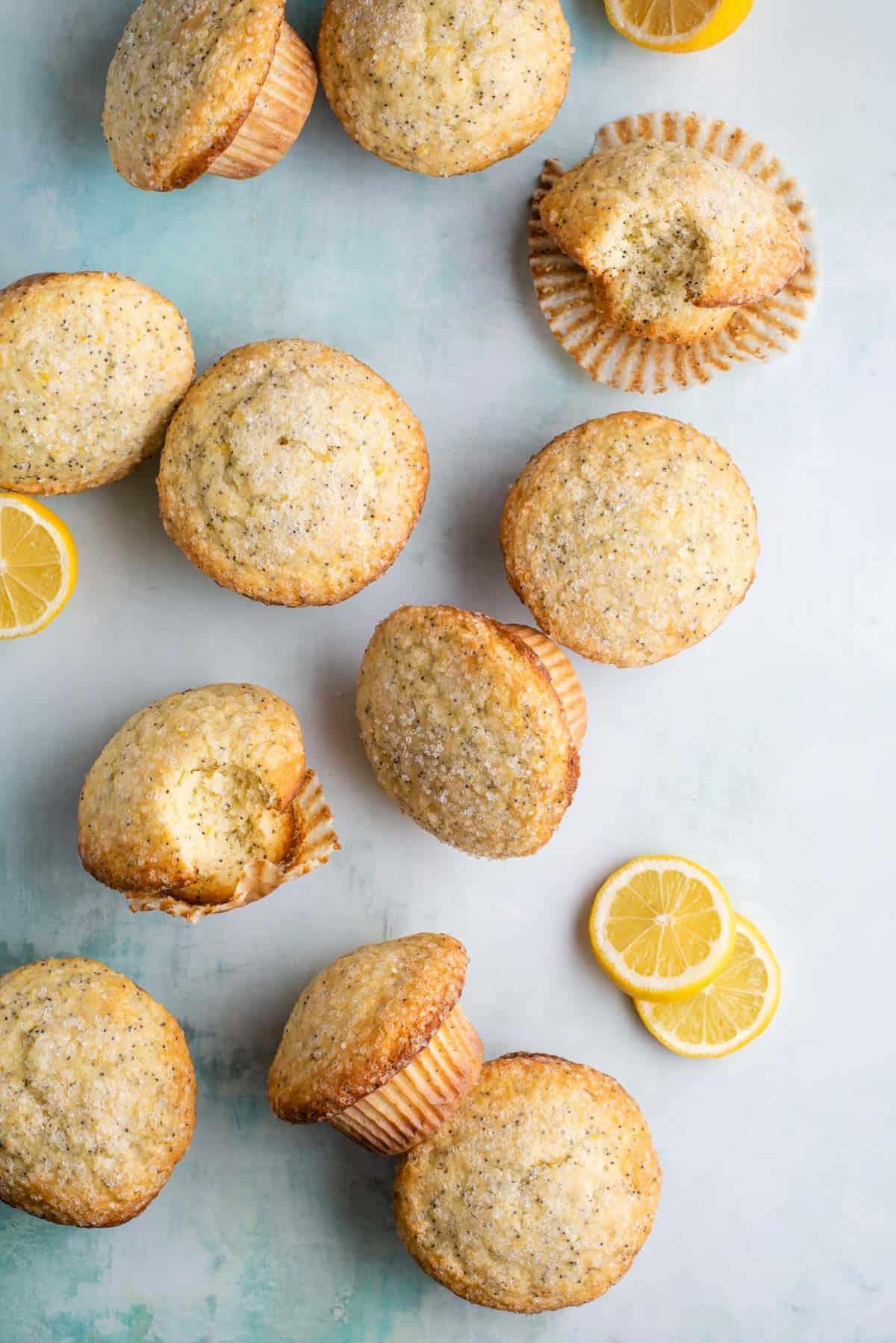 Migliori Muffin al Limone e Semi di Papavero 5 muffin al limone e semi di papavero disposti, alcuni su un lato e altri in posizione verticale, circondati da fette di limone