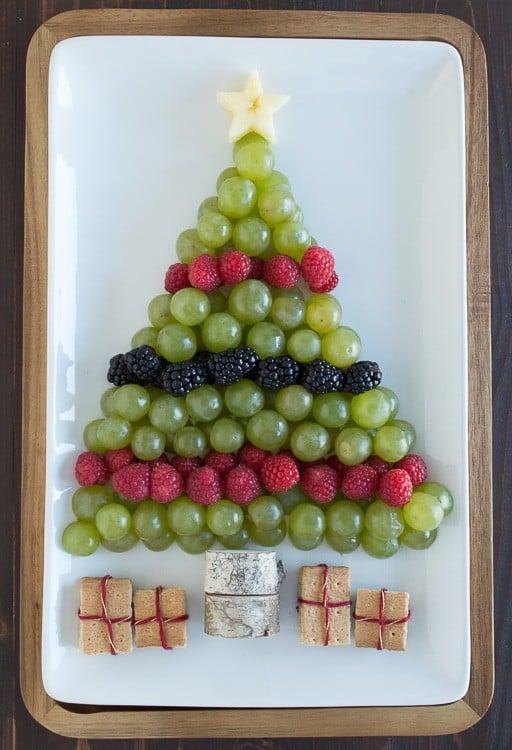 Albero di Natale di Frutta 5 Piatto di frutta a forma di albero di Natale con uva verde, lamponi e more su un vassoio bianco