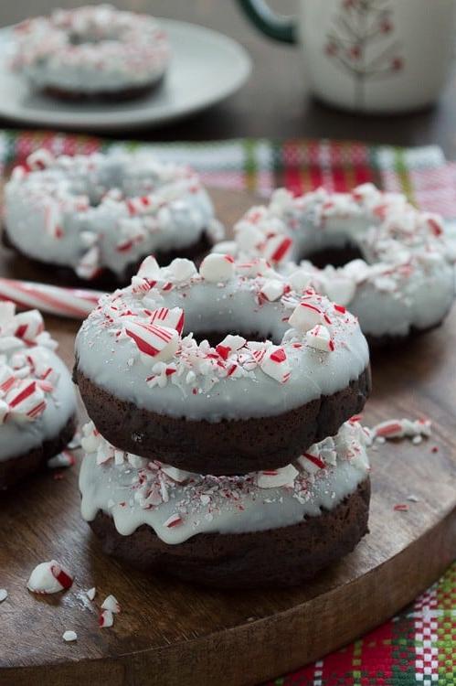 Ciambelle al cioccolato cotte al forno, aromatizzate alla menta piperita, guarnite con cioccolato bianco e bastoncini di zucchero tritati.