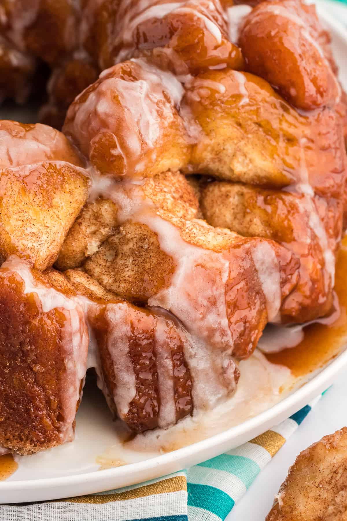 Pane delle scimmie di biscotti 5 Primo piano di Monkey Bread su un piatto bianco con un telo colorato a strisce sotto