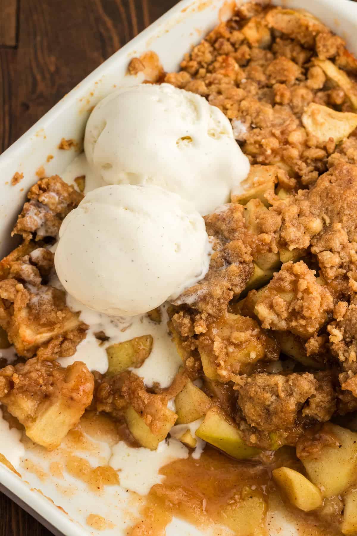 Ricetta Facile di Crumble alle Mele 5 Una pirofila piena di crumble di mele con una porzione mancante e due palline di gelato alla vaniglia sopra
