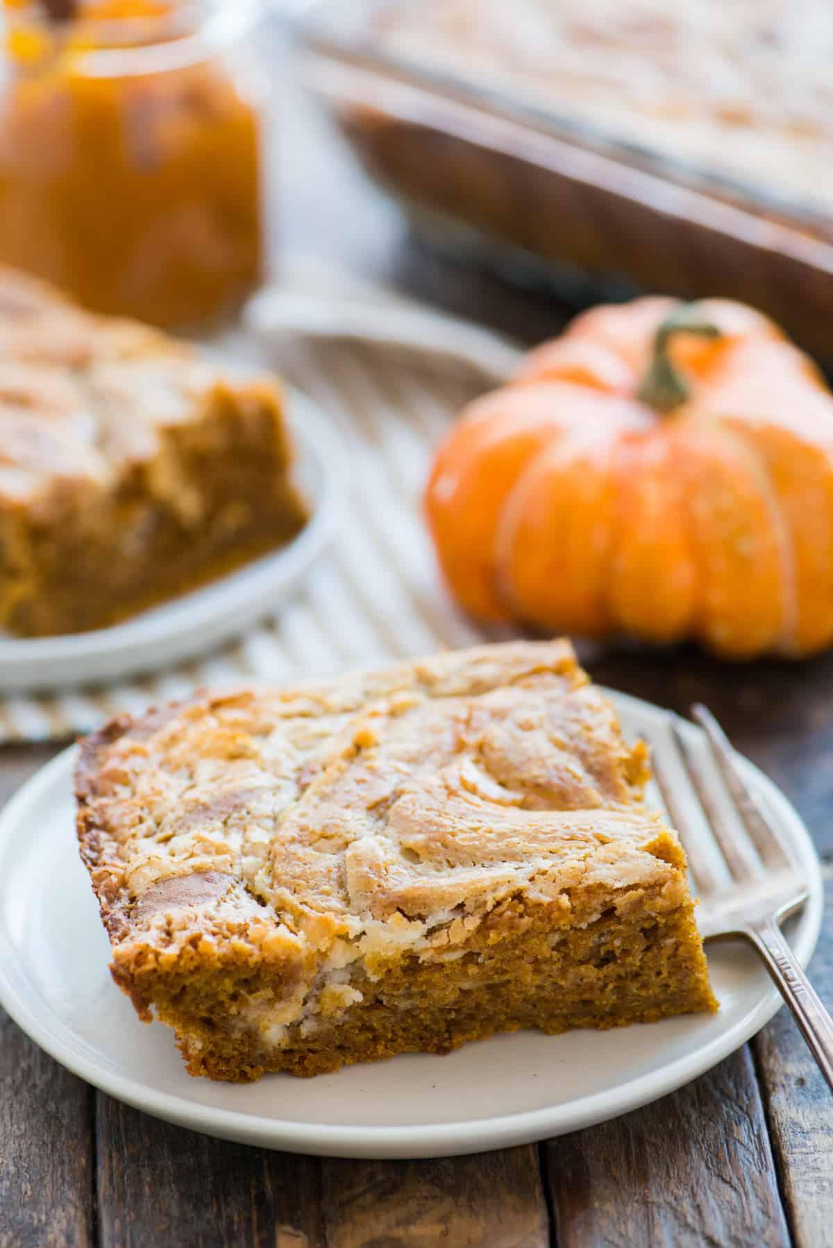 Fetta di torta terremoto alla zucca su piatto bianco con zucca sullo sfondo