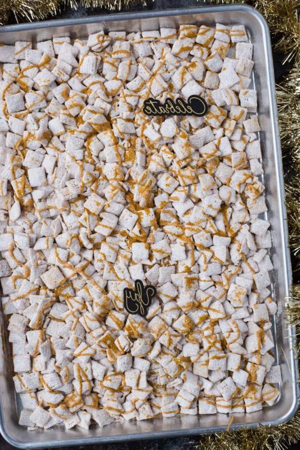 **Dolcetti Croccanti al Cioccolato Bianco di Capodanno** 5 new year’s eve white chocolate puppy chow with gold sprinkles and gold stars on a baking sheet