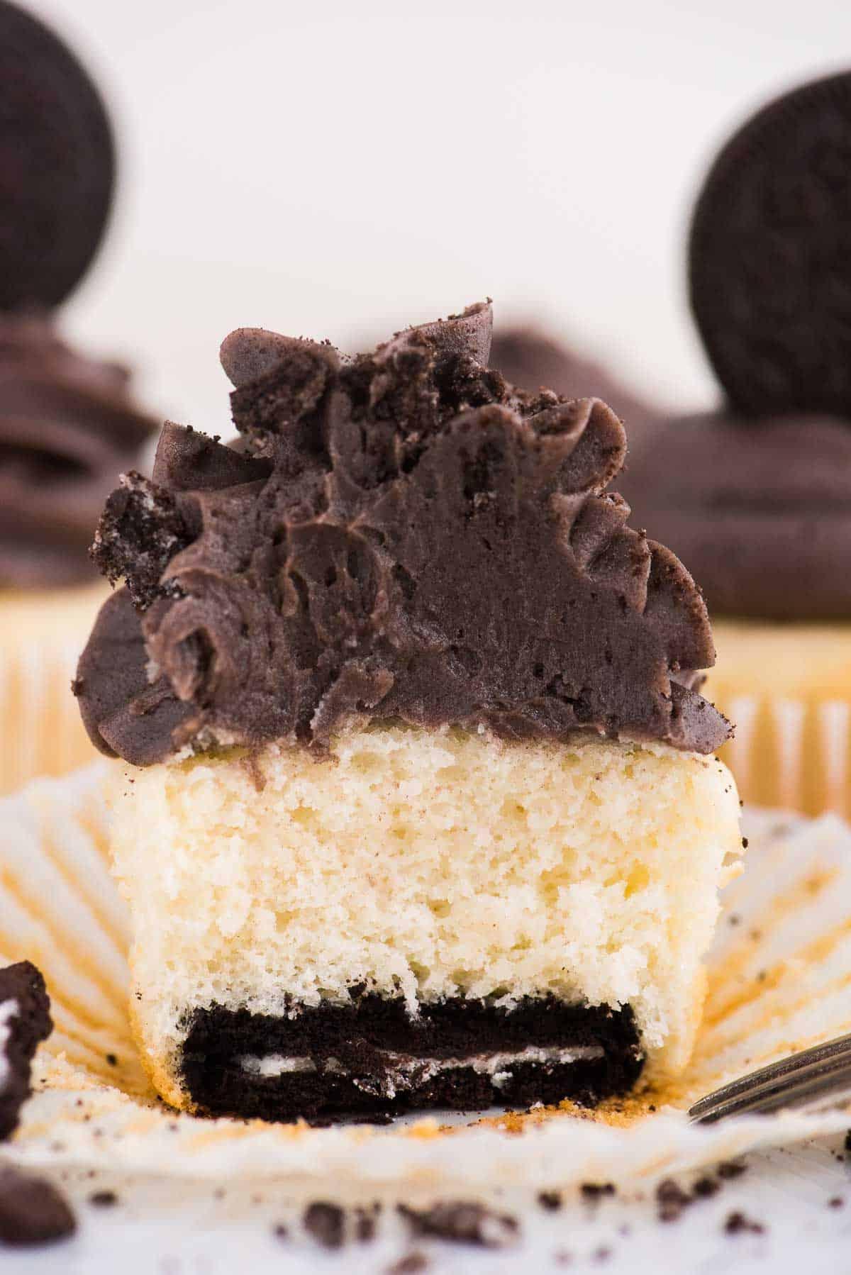 Cupcakes con base Oreo 5 Cupcake alla vaniglia con fondo Oreo tagliato a metà su sfondo bianco