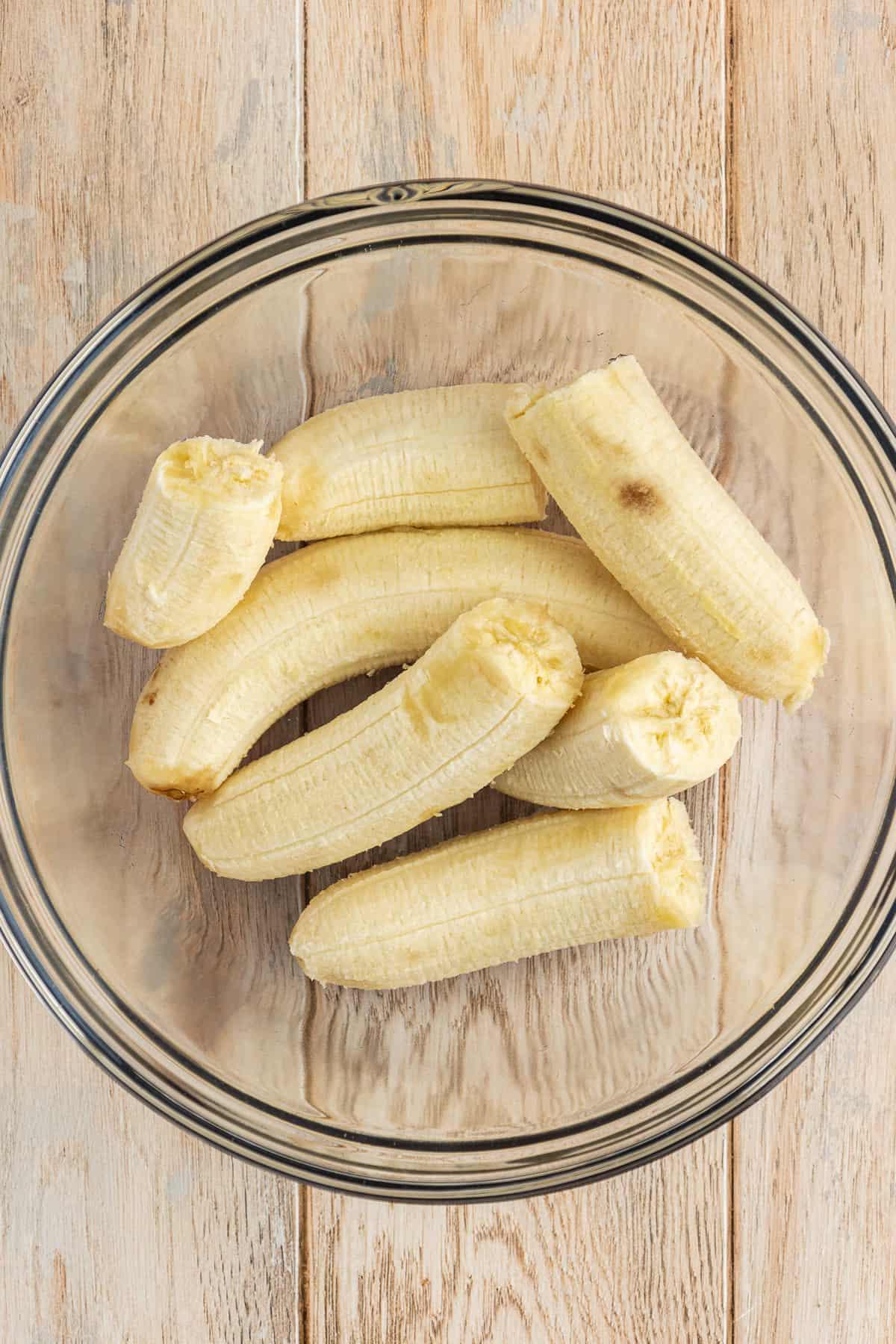 Ricetta Facile Torta alla Banana 6 Una ciotola di vetro piena di metà di banane su una superficie di legno