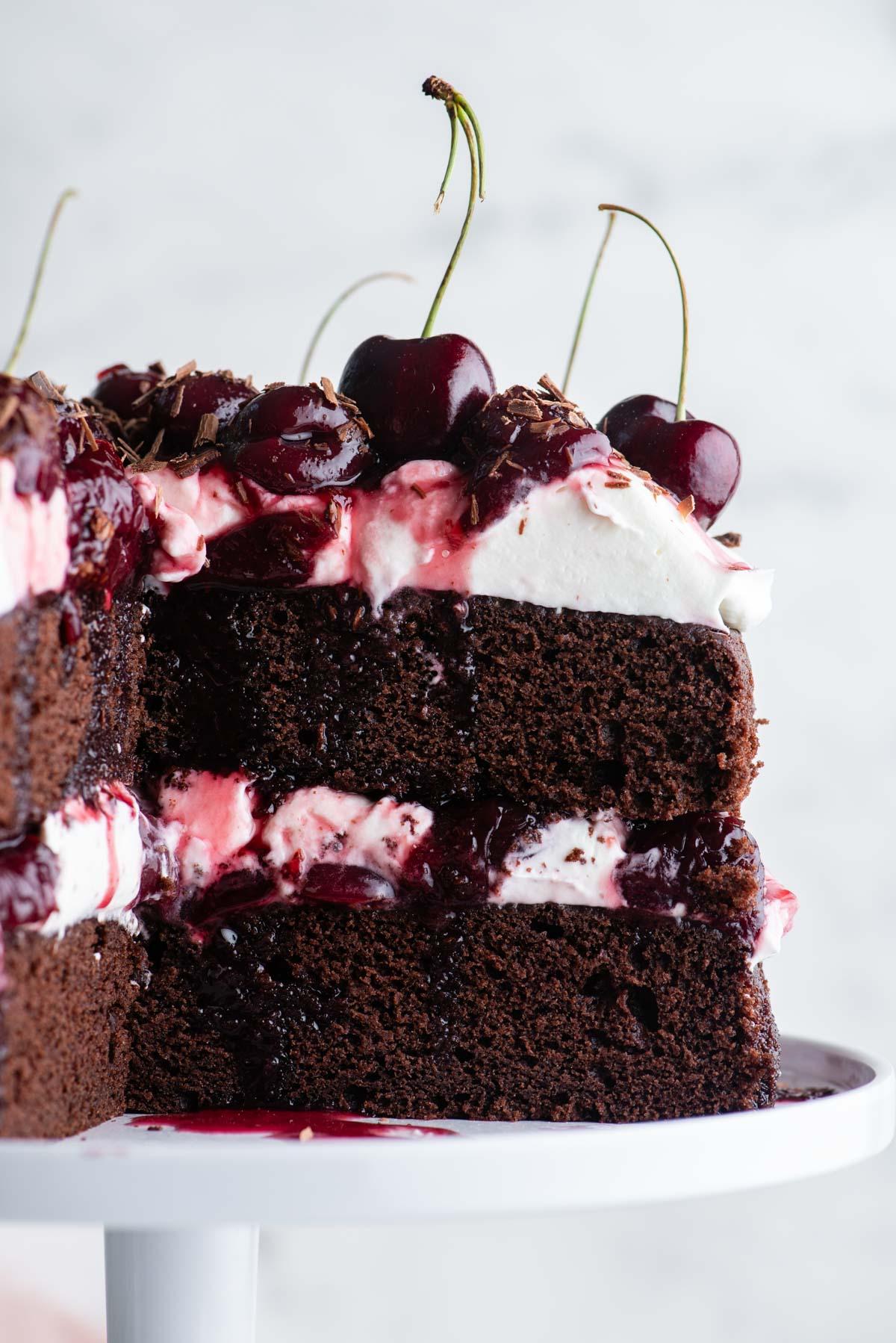 Torta Foresta Nera 6 Primo piano di una Torta Foresta Nera con una grande fetta tagliata, che mostra gli strati di torta, panna montata e ripieno di ciliegie