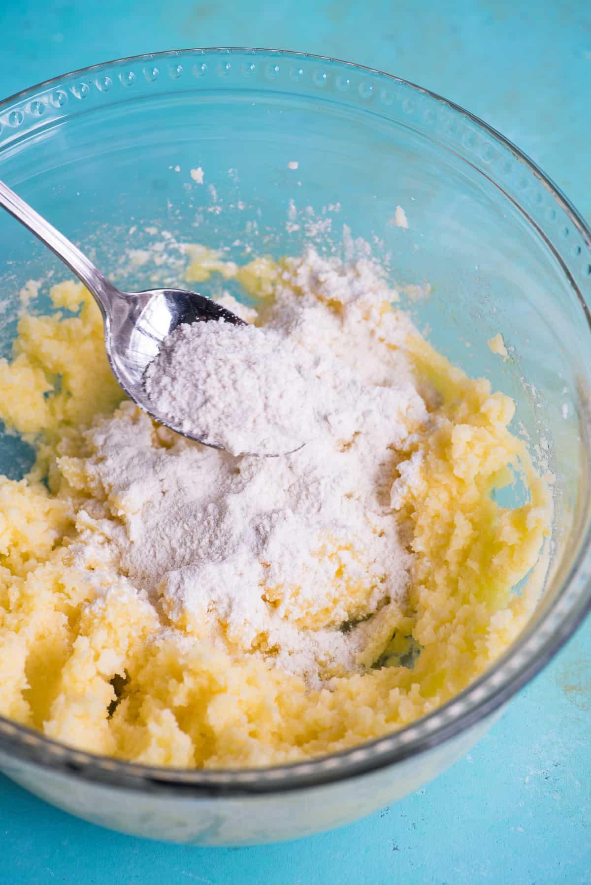 Ricetta Biscotti al Limone 6 Impasto per biscotti con ingredienti secchi in una ciotola di vetro su sfondo blu