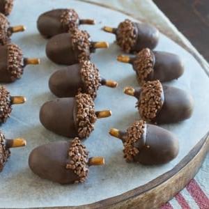 Palline Oreo a forma di ghianda 4 Adorabili e deliziose palline Oreo a forma di ghianda su un tagliere di legno rotondo.