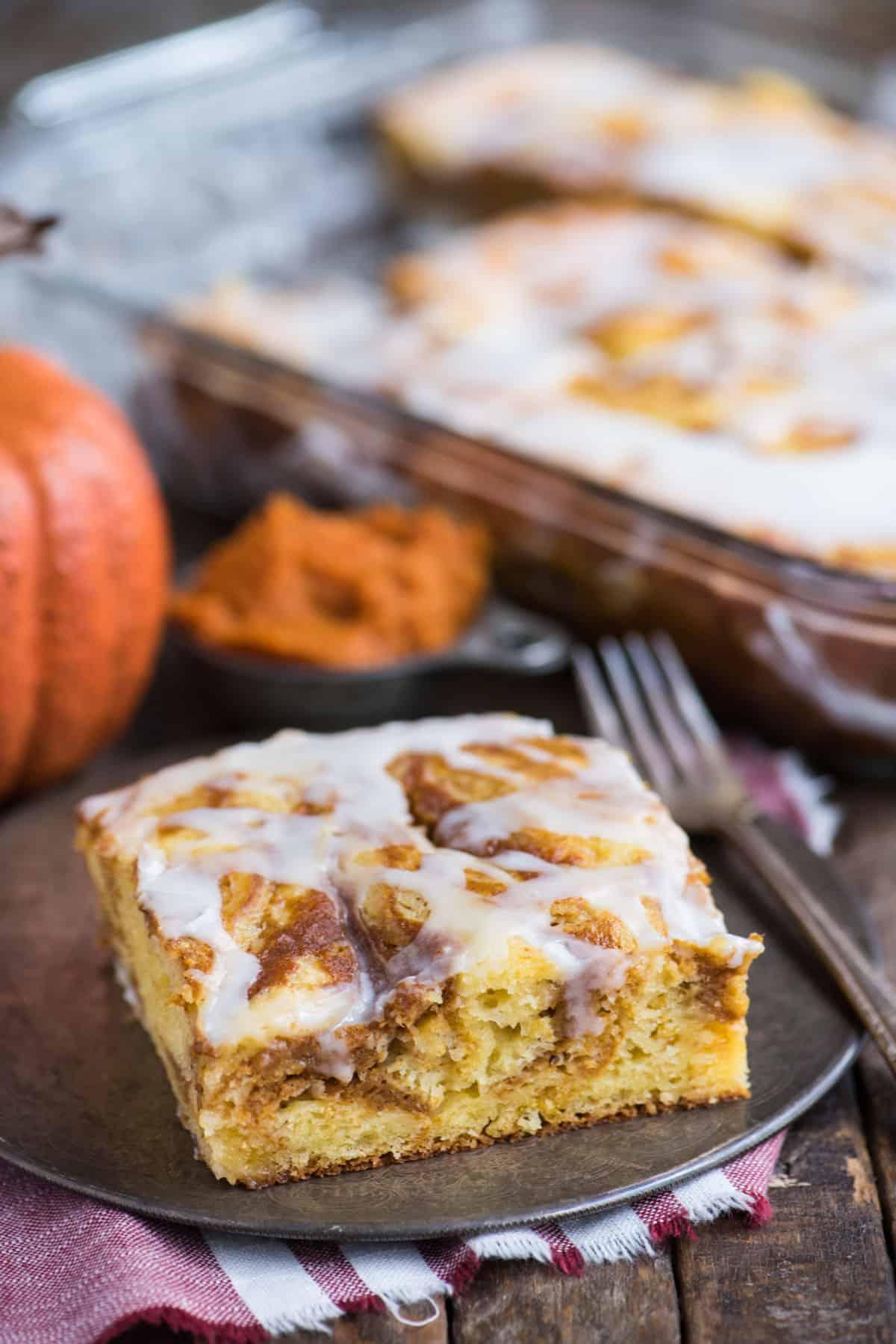 Facile Torta alla Zucca Marmorizzata 6 Fetta di torta soffice alla zucca marmorizzata con glassa bianca su un piatto di metallo.
