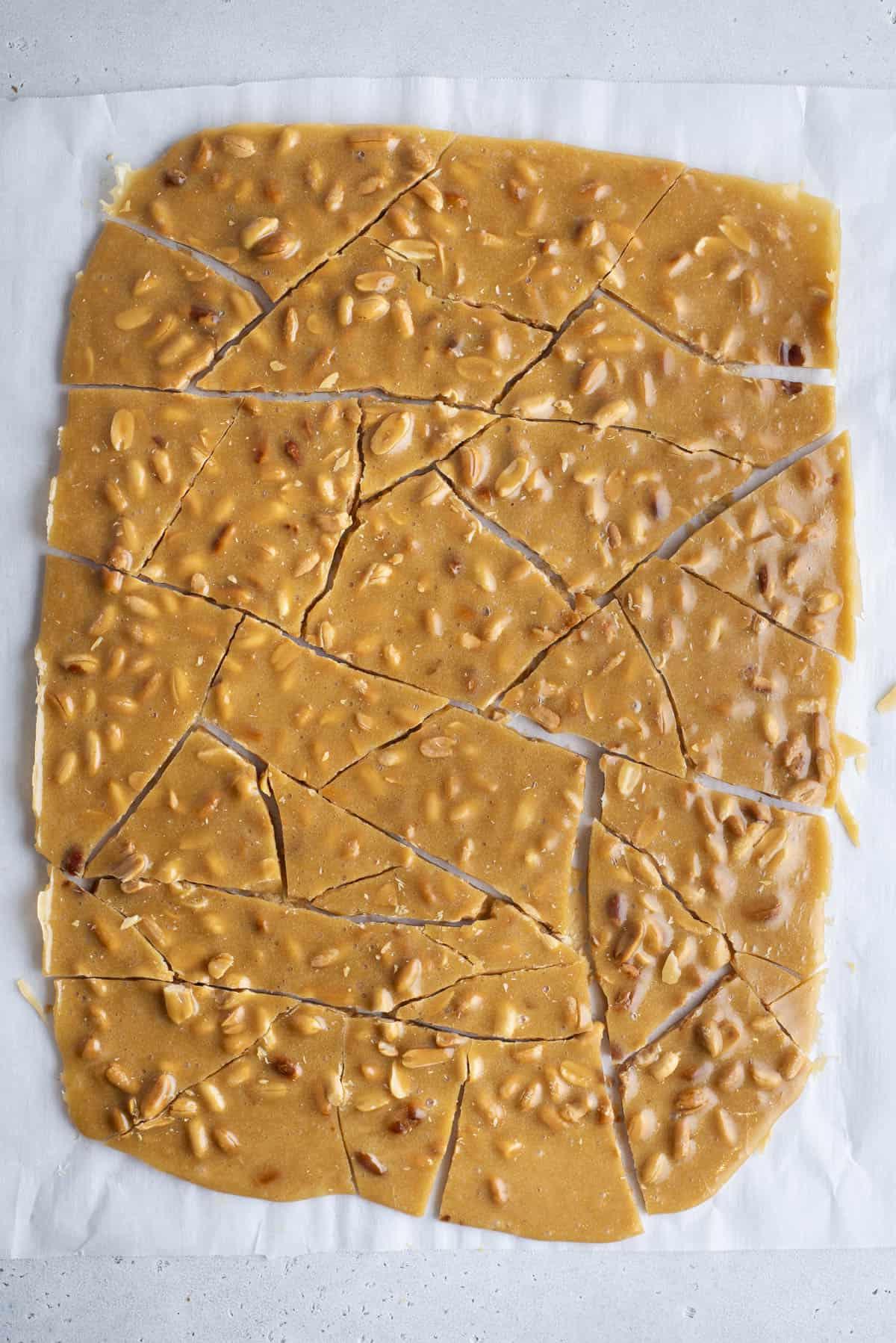 Il miglior croccante di arachidi 6 Croccante di arachidi rotto a pezzi su una teglia rivestita di carta da forno