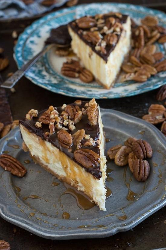 Questa è la migliore cheesecake tartaruga! È ricca e così cremosa. Guarnita con ganache al cioccolato, noci pecan e salsa al caramello.