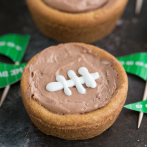 **Coppette Football di Biscotti allo Zucchero** 6 Un biscotto a tazza a tema football con cheesecake e cuciture bianche di glassa reale.