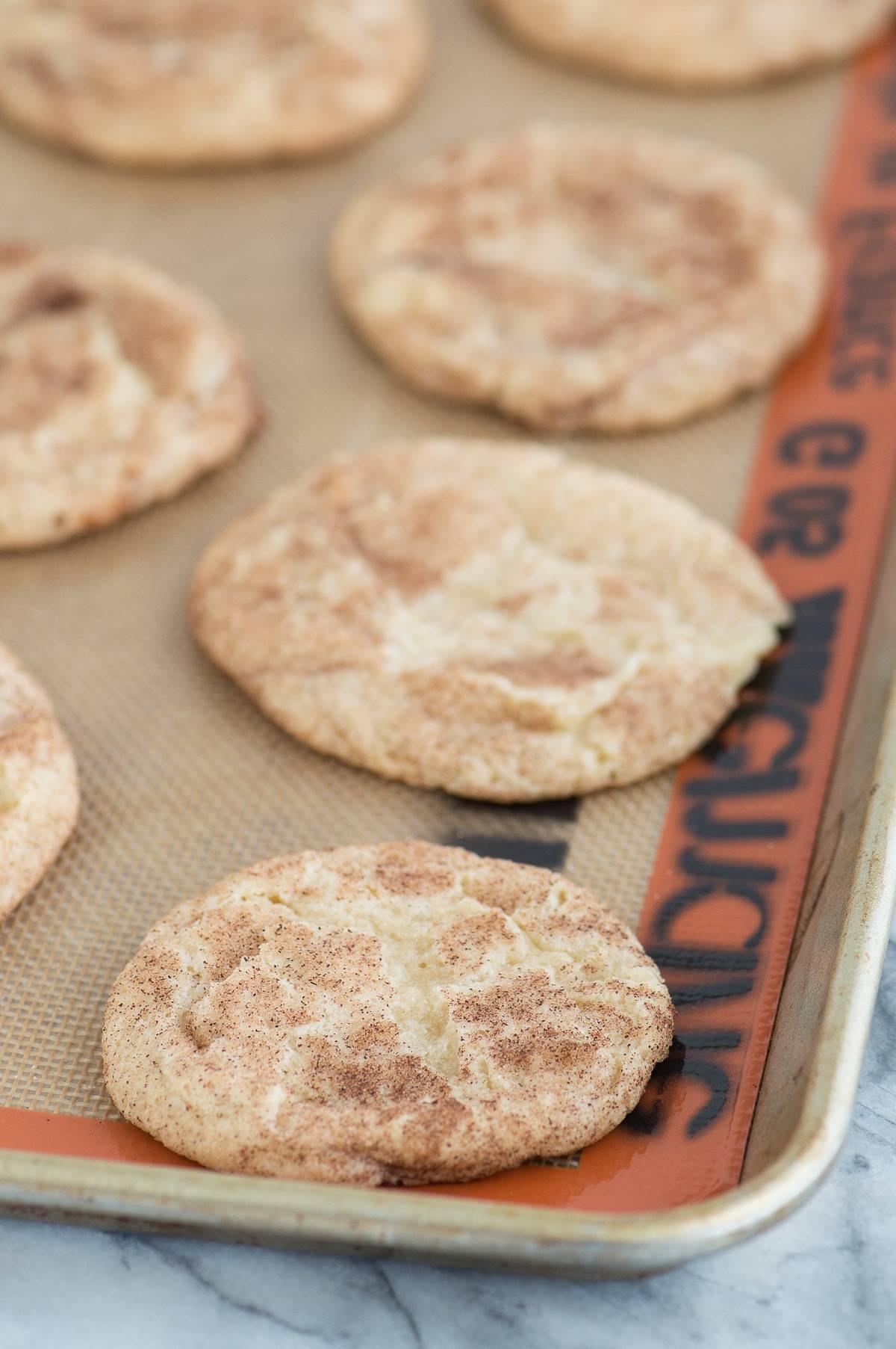 Snickerdoodles al Caramello e Mela 6 Snickerdoodle alle mele caramellate allineati su un tappetino di silicone su una teglia metallica