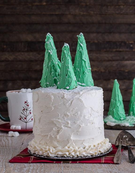 Dettaglio degli alberi di Natale fatti con coni gelato, glassati di verde e spolverati di zucchero a velo, pronti per decorare la torta