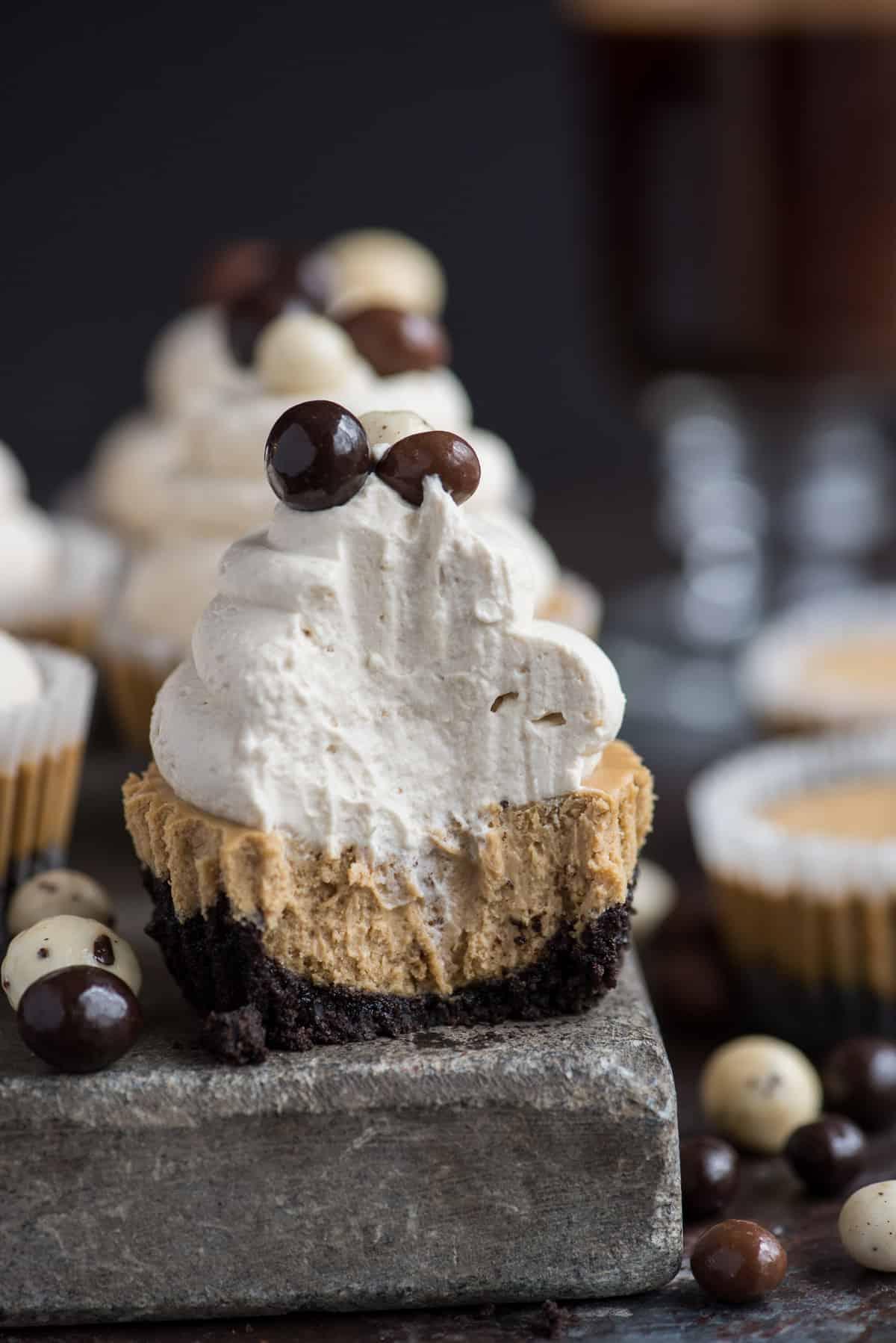 Questa è una ricetta di mini cheesecake al caffè che piacerà a tutti e che userai più e più volte! L'intera ricetta richiede solo 7 ingredienti e la prepari in uno stampo per muffin di dimensioni normali! Inoltre, puoi fare una base di Oreo o una base di cracker Graham per queste mini cheesecake all'espresso. #minicheesecake #coffeecheesecake #minicoffeecheesecake #espressocheesecake #mochacheesecake Mini cheesecake al caffè su lastra di pietra con panna montata e chicchi di caffè espresso