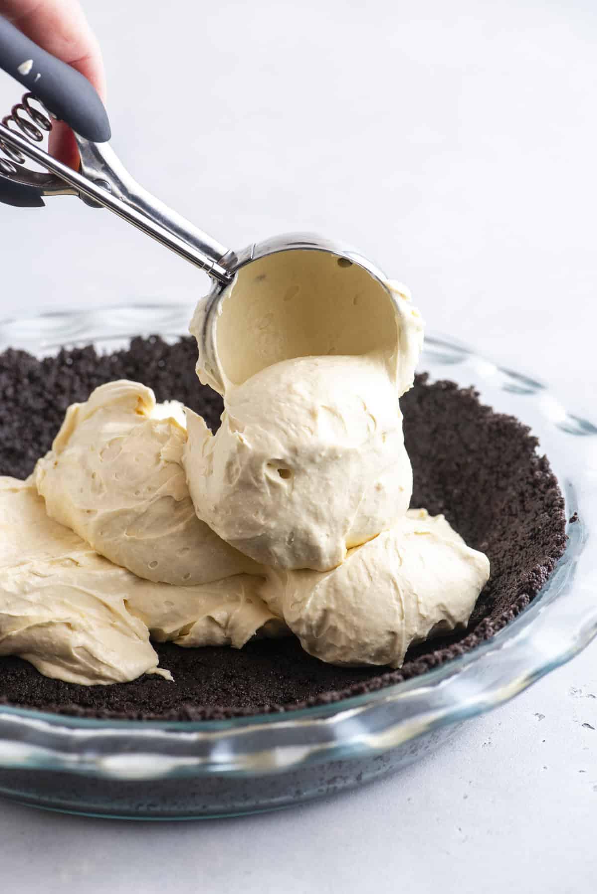Torta di Tartaruga 6 Base di Oreo in un piatto di vetro con ripieno cremoso al caramello che viene versato sopra.