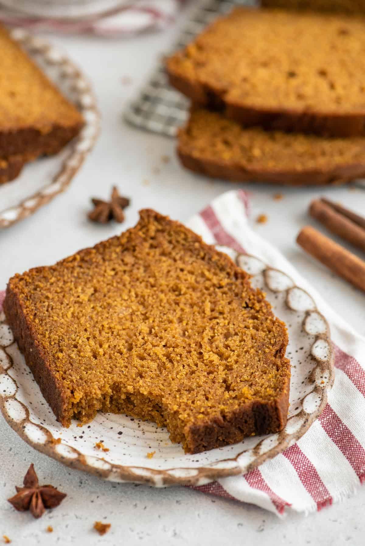 Una fetta di pane di zucca senza glutine con un morso mancante è posata su un piccolo piatto.
