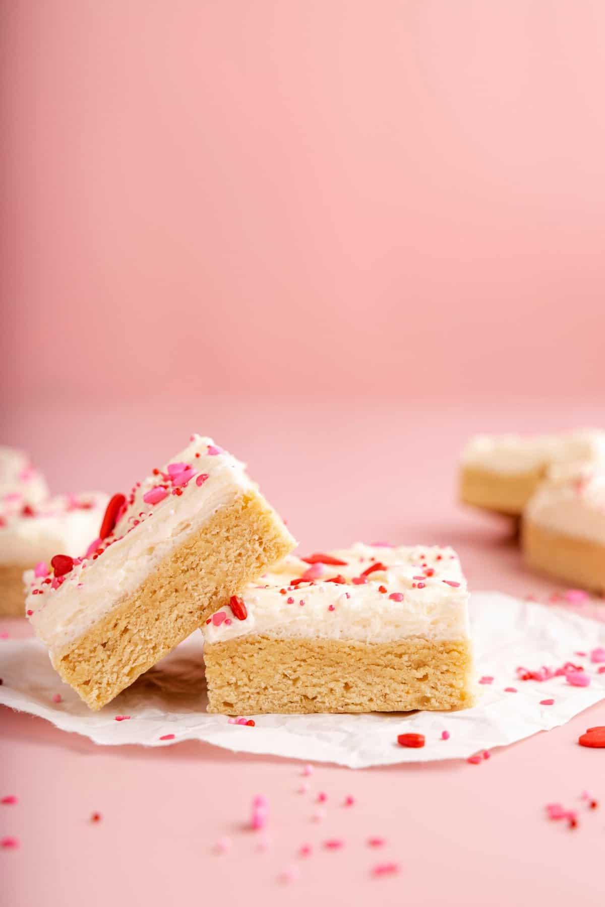 Quadrotti di Biscotti di Zucchero di San Valentino 7 due barrette di biscotto zuccherato con glassa bianca e confettini a tema San Valentino su sfondo rosa