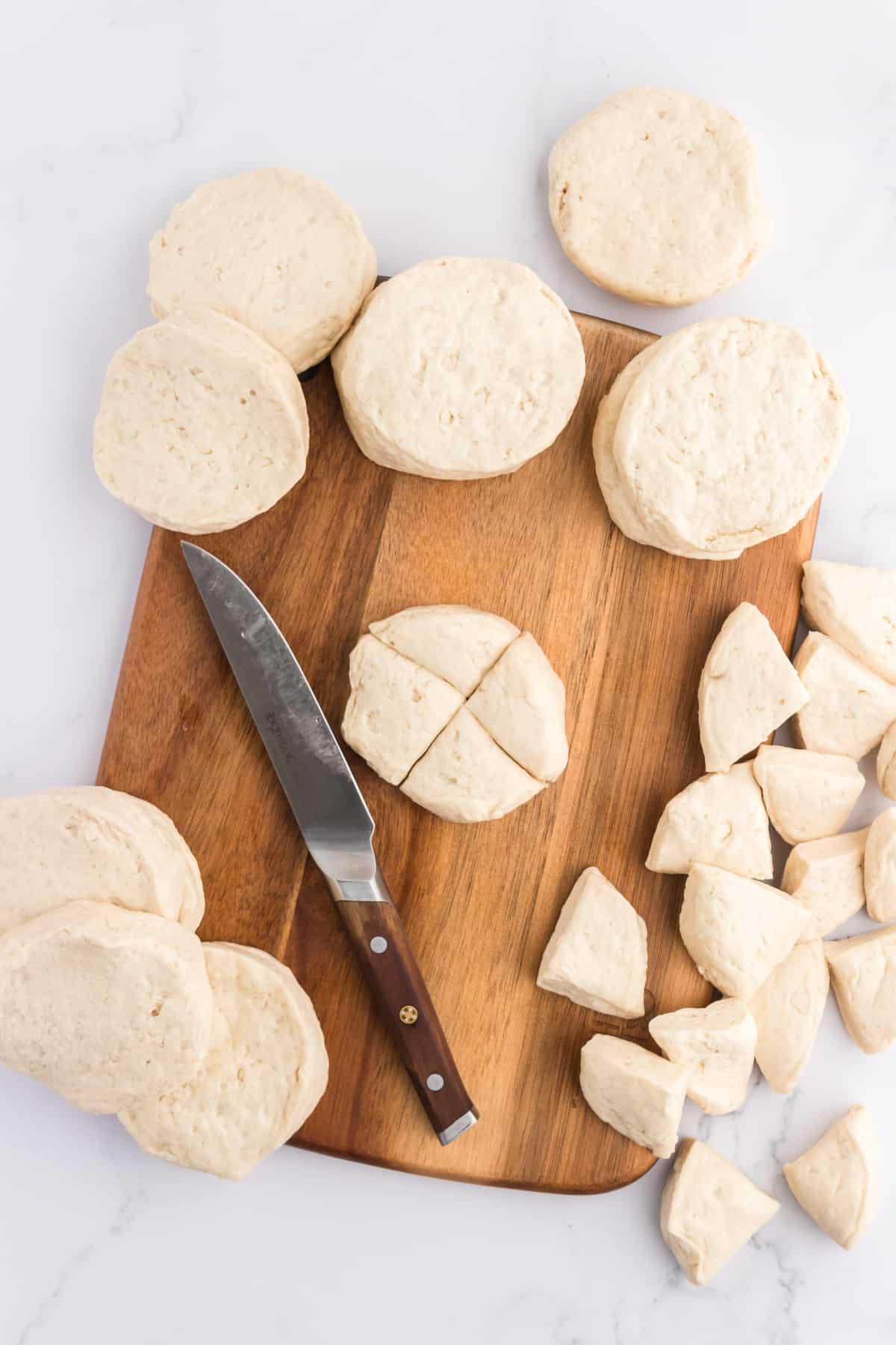 Pane delle scimmie di biscotti 7 Biscotti refrigerati su un tagliere con un coltello, alcuni biscotti tagliati in quattro pezzi