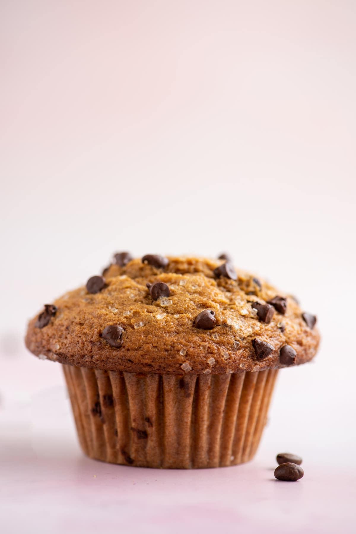 un muffin al cappuccino con gocce di cioccolato su una superficie bianca e rosa chiaro