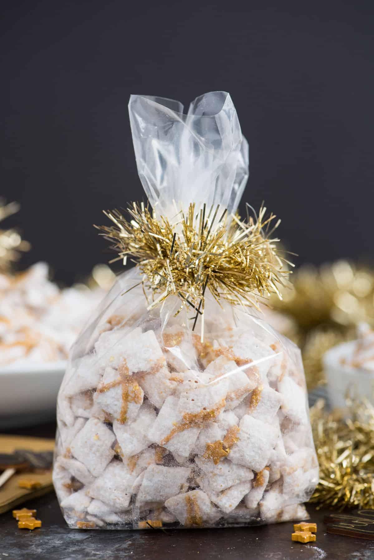 **Dolcetti Croccanti al Cioccolato Bianco di Capodanno** 7 new year’s eve white chocolate puppy chow with gold sprinkles and gold stars inside a cellophane bag with gold ribbon
