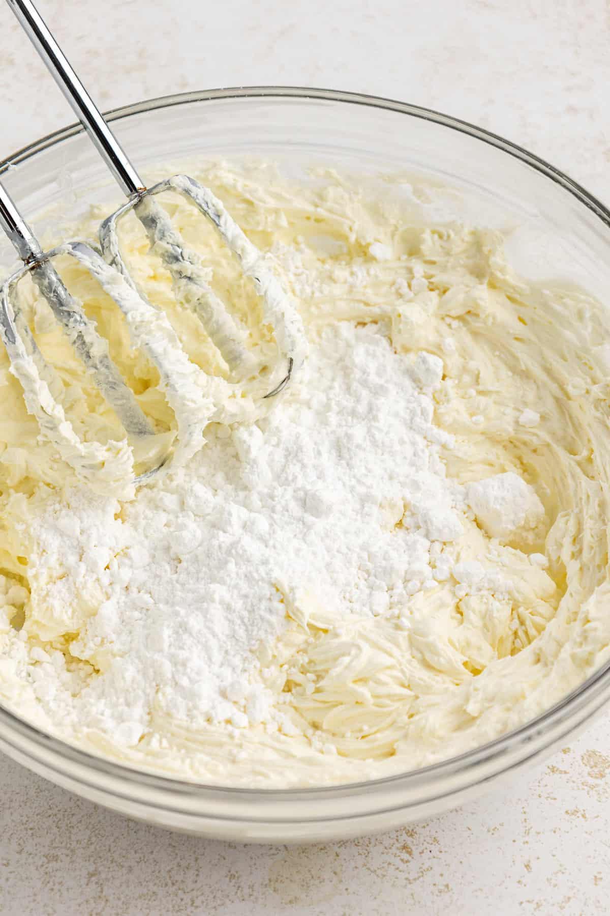 La migliore ricetta per la Torta al Fango 7 Una miscela di crema di formaggio, burro e zucchero a velo viene sbattuta in una grande ciotola di vetro trasparente con un mixer elettrico