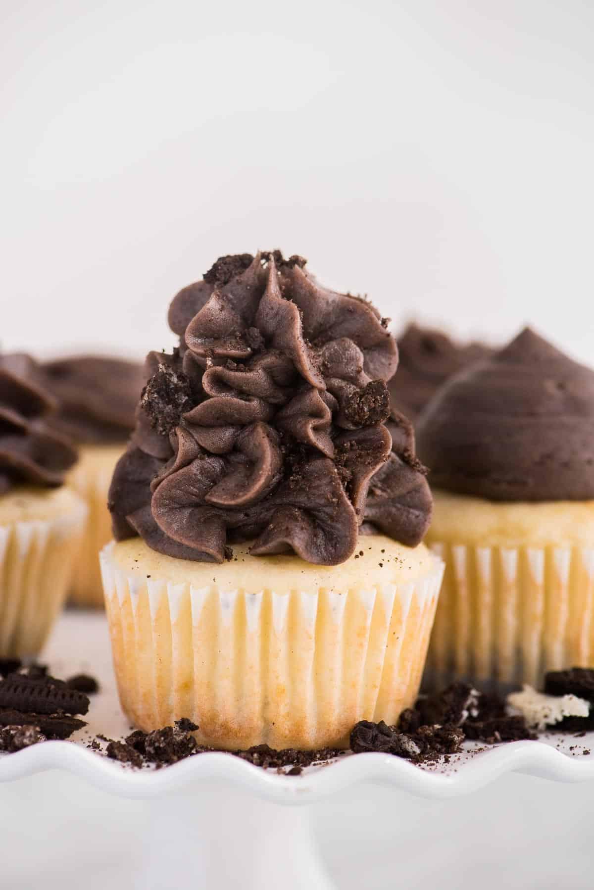 Cupcakes con base Oreo 7 Cupcakes alla vaniglia con fondo Oreo su alzata bianca su sfondo bianco