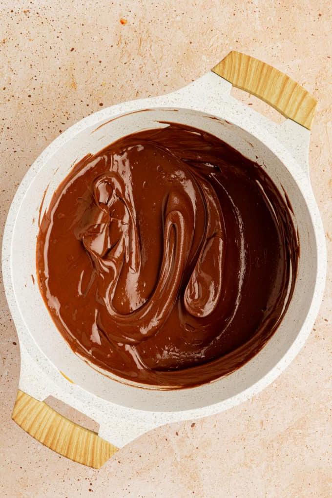 Una miscela fusa di gocce di cioccolato, burro d'arachidi e burro in una pentola bianca
