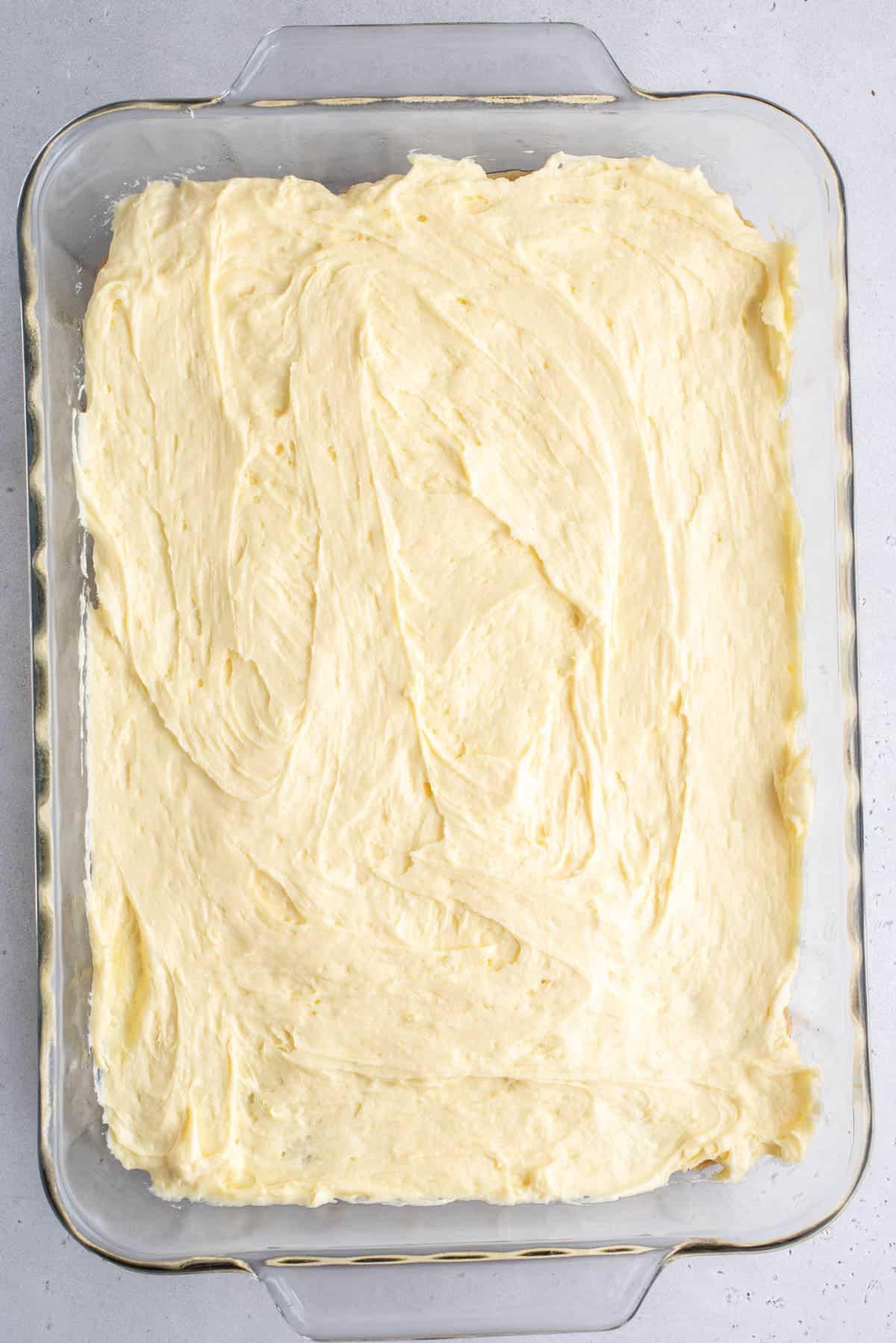 Brownies al Budino di Banana 7 Una teglia trasparente con i primi due strati di brownies al budino di banana, lo strato blondie e lo strato di miscela di budino di banana