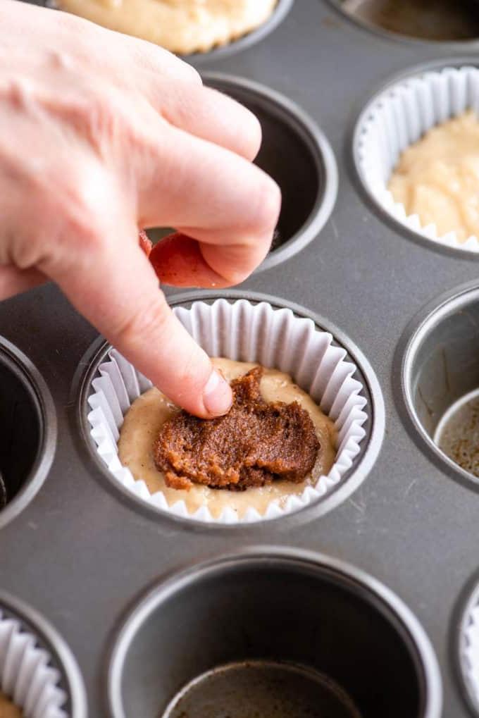 Muffin alla Sbriciolata 8 dito che preme la miscela di zucchero e cannella nell'impasto del muffin
