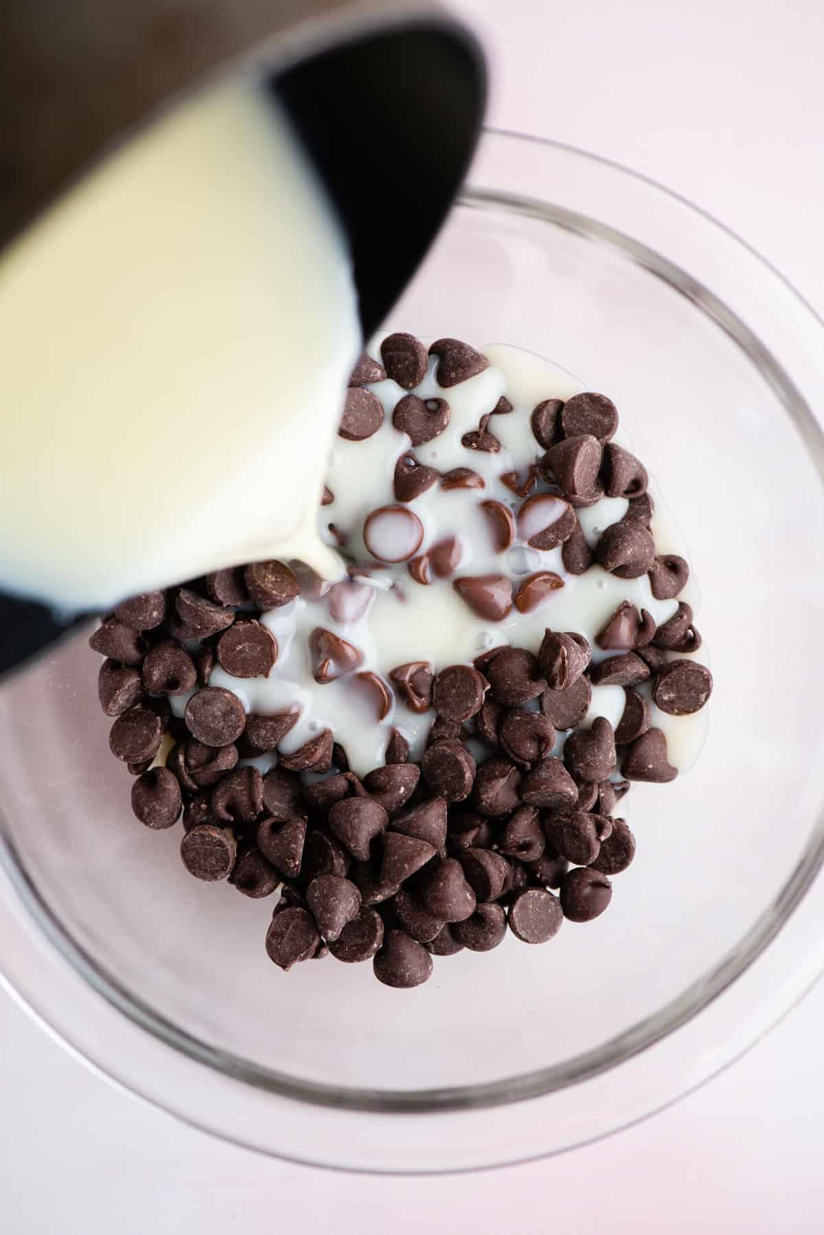 **Salsa Calda al Cioccolato Fondente** 8 Una miscela di panna fresca e zucchero versata su una ciotola di vetro di gocce di cioccolato per fare la salsa hot fudge fatta in casa