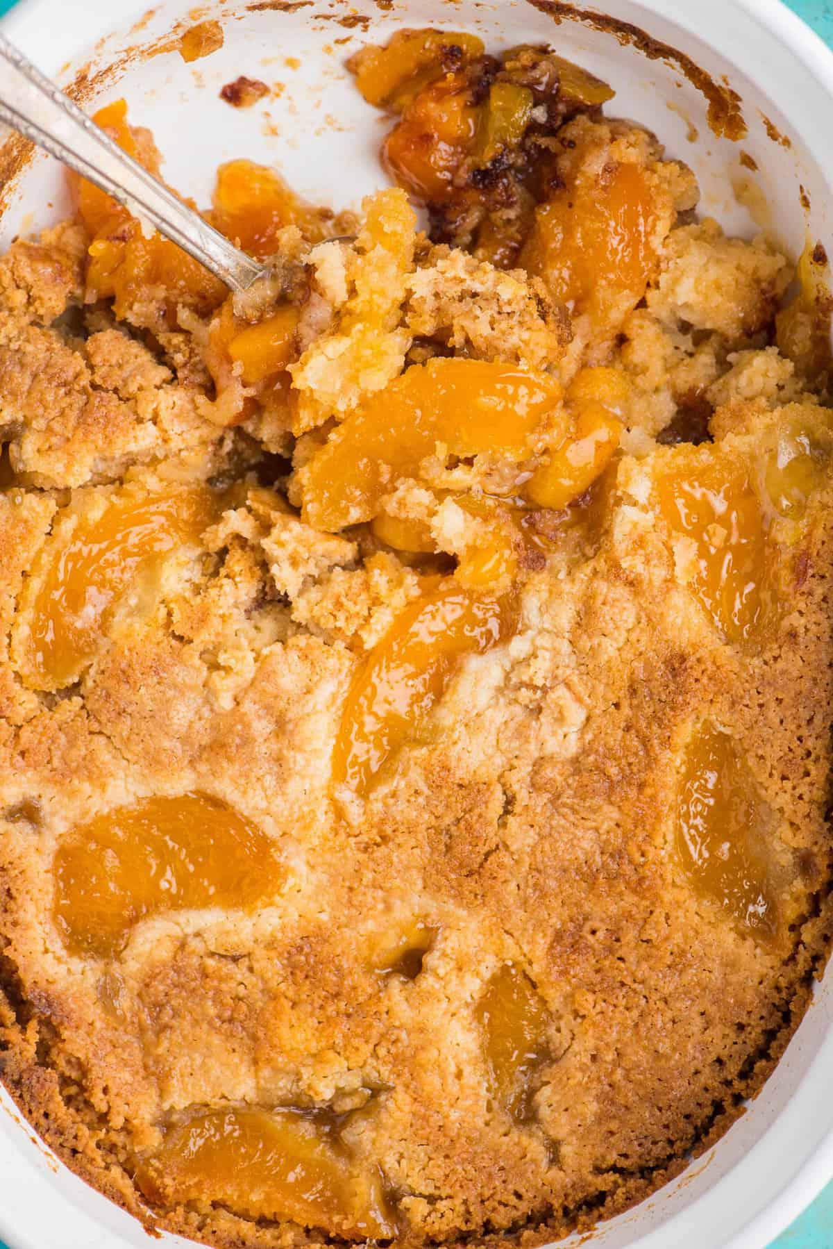 Torta Facile di Pesche con Preparato per Torta 8 torta di pesche dump cake con cucchiaio in teglia bianca