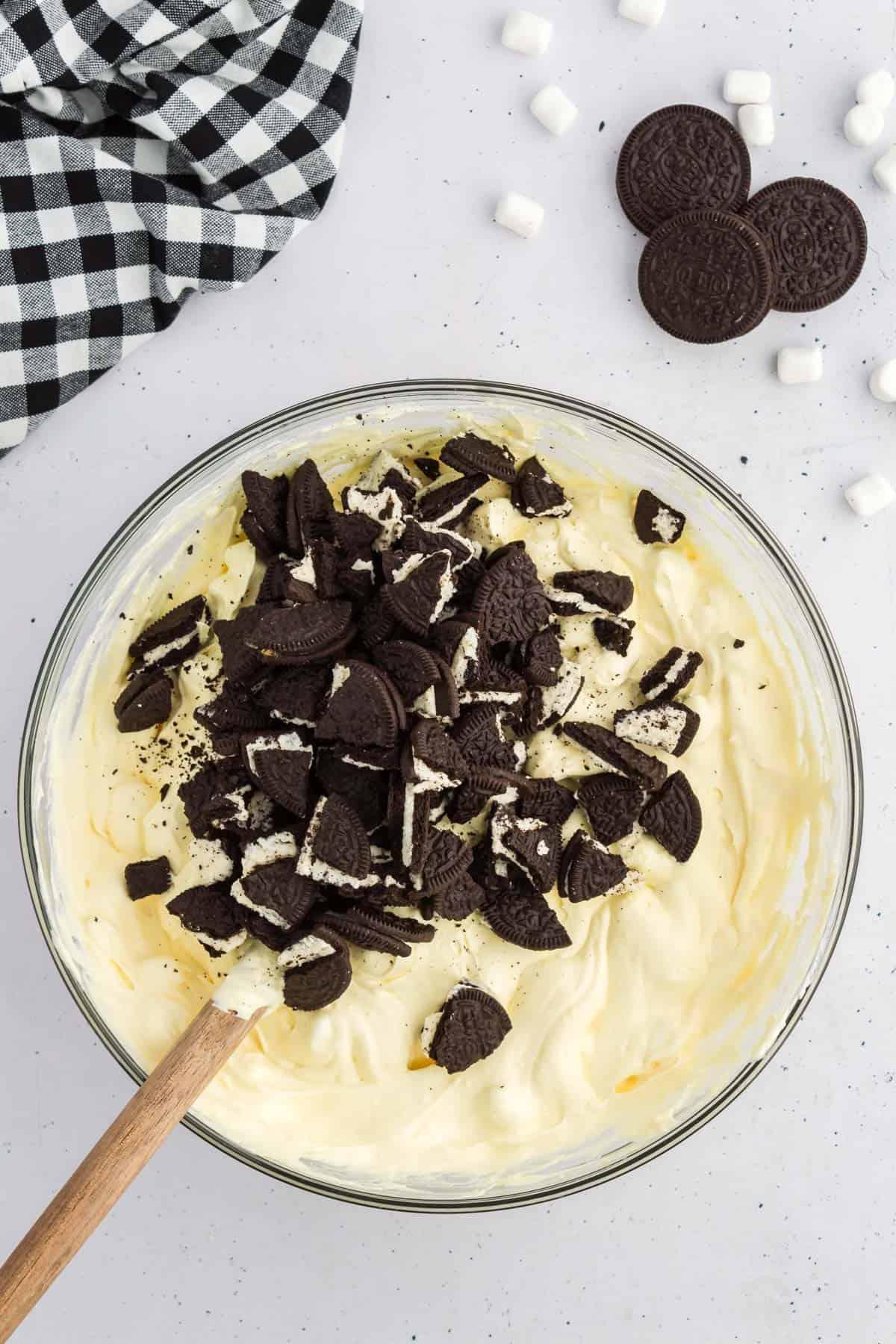 Ricetta Crema Soffice Oreo (Senza Formaggio Cremoso) 8 Miscela di fluff di Oreo sormontata da Oreo tritati, circondata da Oreo, mini marshmallow e un panno da cucina a scacchi bianchi e neri