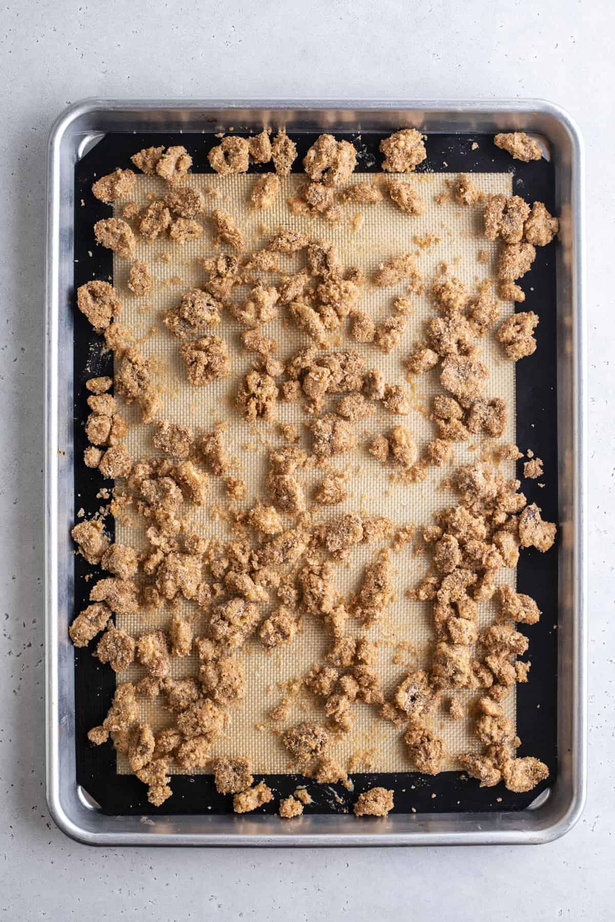 noci pralinate sparse su una teglia foderata con un tappetino da forno in silicone