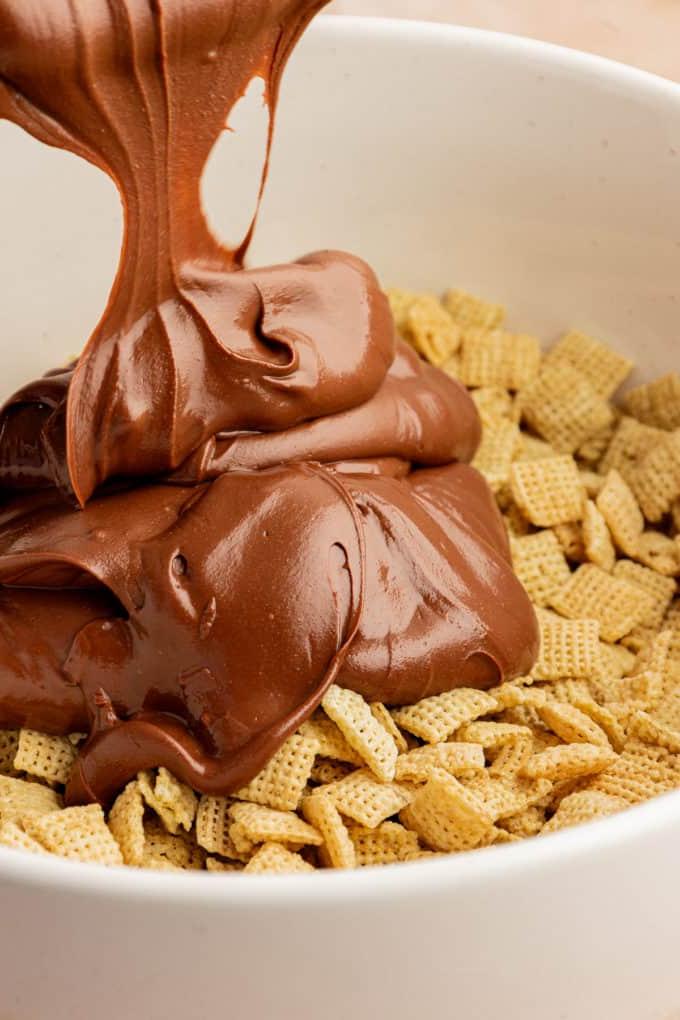 Una miscela di cioccolato fuso e burro d'arachidi versata sui cereali chex in una ciotola bianca