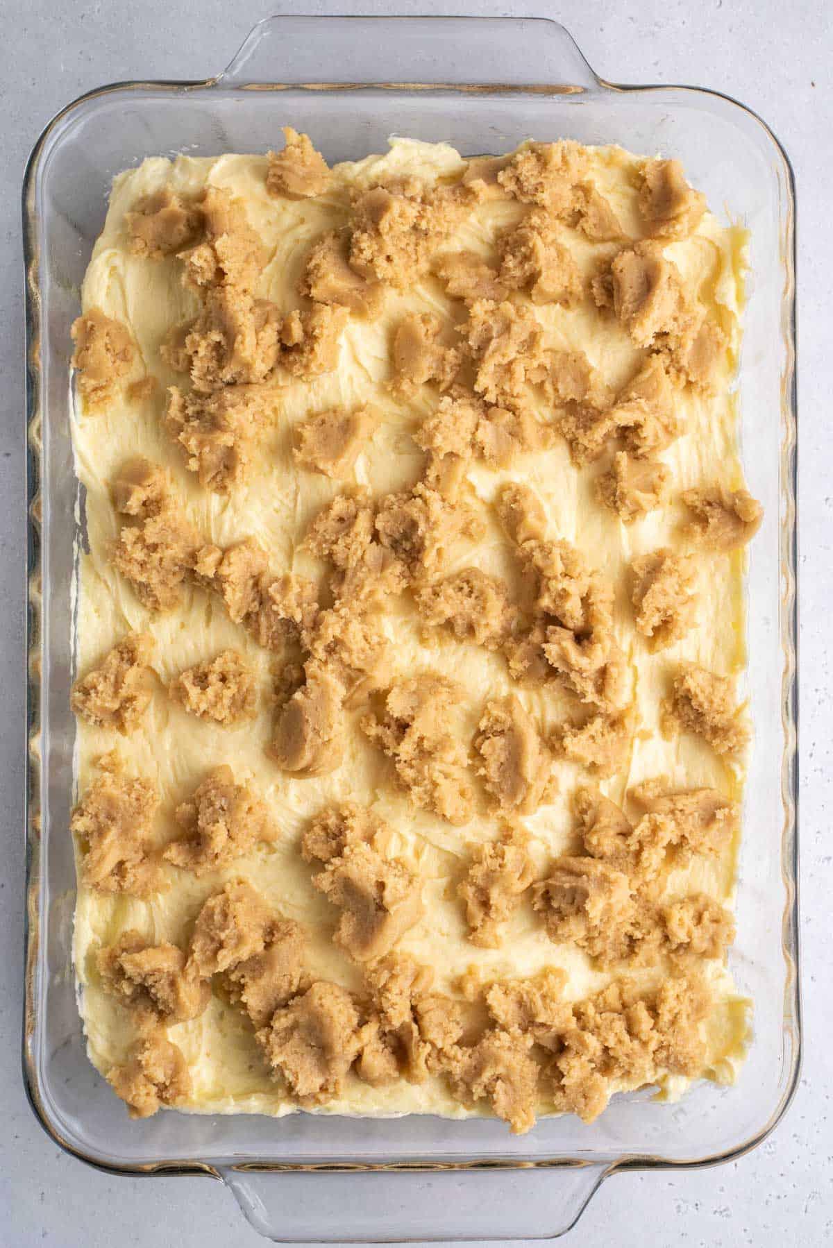 Brownies al Budino di Banana 8 Una teglia trasparente con gli strati di brownies al budino di banana, lo strato blondie, la miscela di budino di banana e un altro strato di miscela blondie prima della cottura