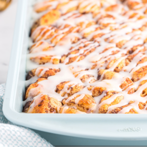 Facile Sformato di Girelle alla Cannella 8 A close-up of a cinnamon roll casserole showcases golden-brown rolls packed together, generously drizzled with white icing. The soft, fluffy breakfast casserole looks irresistibly sweet and ready to enjoy.