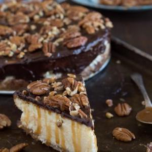Questa è la migliore cheesecake tartaruga! È ricca e così cremosa. Guarnita con ganache al cioccolato, noci pecan e salsa al caramello.