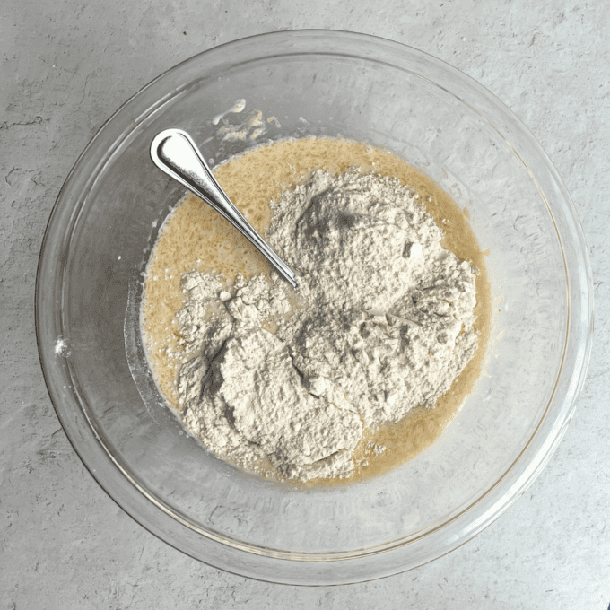 Pancakes Soffici Fatti in Casa 9 Ingredienti liquidi e secchi per i pancake in una ciotola di vetro trasparente con una forchetta.